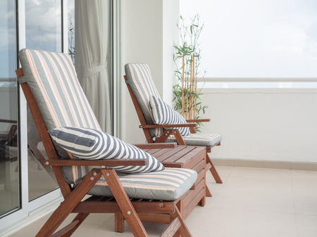 Wooden Sunbed with Pillows in The Terrace near Sliding Door and Bamboo on Sky Background with Space.