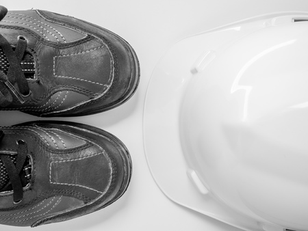 flat lay white hard Safety helmet with black leather safety shoes isolated on white background top view.の写真素材