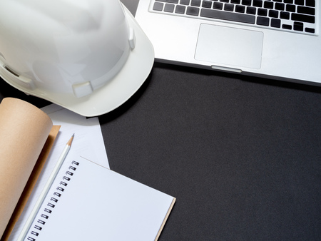 flat lay white hard Safety helmet with laptop, notebook, paper and pencil for engineering worker on black background top view with space.の写真素材