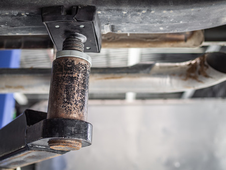 Close-up detail of car repair lift machine in automobile service garage, under the car view with copy space.の写真素材