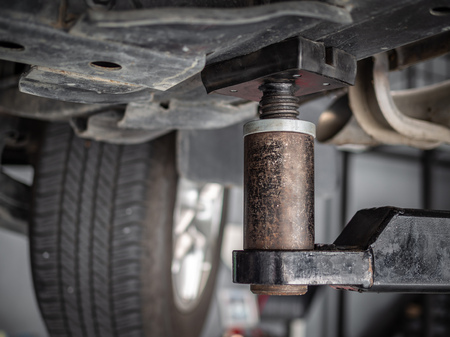 Close-up car repair lift machine in automobile service garage, under the car view.の写真素材