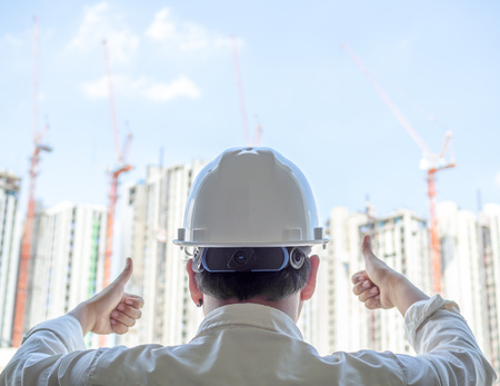Engineer man back view wearing white hard safety helmet and white shirt showing thumbs up for...