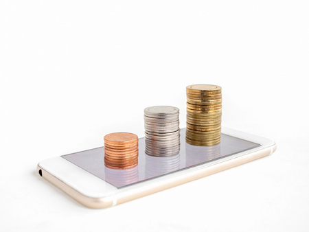 Making money online. Business financial online concept. money, stack of copper, silver and gold coins on mobile Phone isolated on white background with copy space.の写真素材