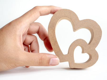 Hand touching wooden twin heart, Couple heart isolated on white background. Love, Family, valentine's day concept.の写真素材