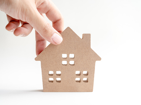 Hand putting wooden house isolated on white background. Property investment and family concept.の写真素材