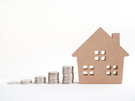 Money coins stack with wooden house isolated on white background with copy space. Property investment financial concept.の写真素材