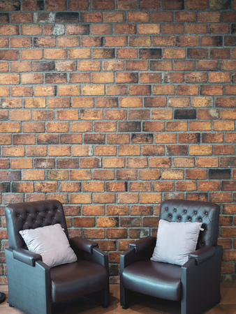 Loft interior concept. Two leather sofa and pillows on Brick wall background with copy space vertical style.の写真素材