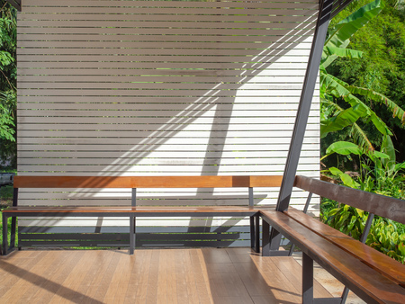 Long wooden table with white wooden wall in outdoor living room on green jungle backgroud.の写真素材