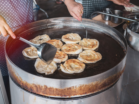 Fried indian bread roti in big pan. Hands making traditional indian food. Roti oil.の写真素材
