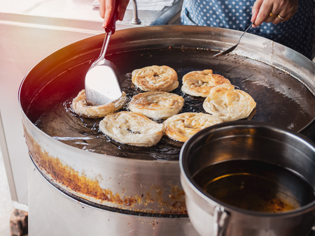 Fried indian bread roti in big pan. Hands making traditional indian food. Roti oil.の写真素材