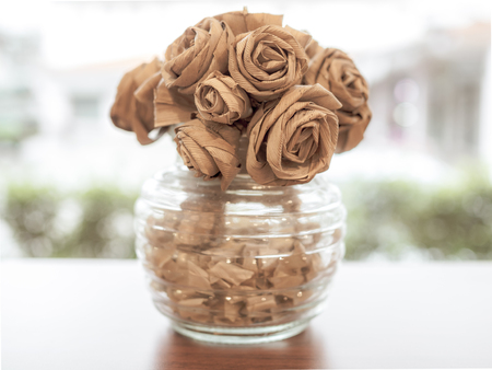 Rose flowers weaving handcraft in glass bottle on wooden table vintage style.の写真素材