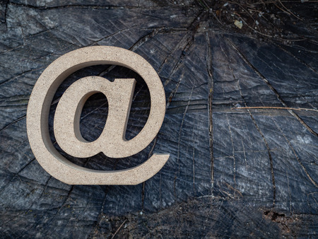Wooden E-mail address symbol, arroba icon on old dry wooden texture background. E-mail marketing online internet, technology and environment concept.の写真素材
