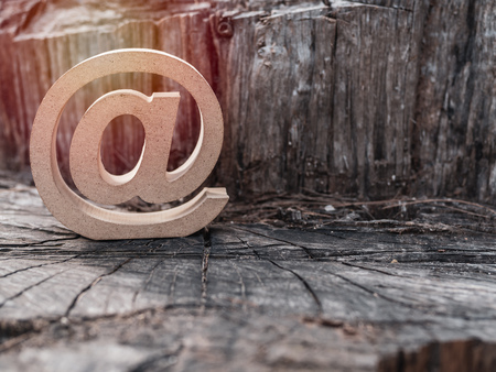 Wooden E-mail address symbol, arroba icon on old dry stump texture background. E-mail marketing online internet, technology and environment concept.の写真素材