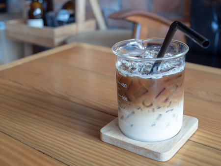 Ice coffee in beaker cup with black tube on wooden table in cafe. coffee unique concept with copy space.の写真素材