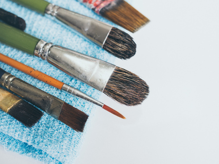 Row of artist paintbrushes on blue small towel isolated on white background with copy space vintage style.の写真素材