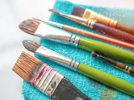 Row of artist paintbrushes on blue small towel on white background.の写真素材