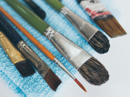 Row of artist paintbrushes on blue small towel isolated on white background vintage style.の写真素材