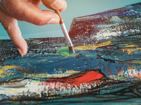 Close-up artist hand painting. Concentrate painting acrylic color on canvas in art studio.の写真素材