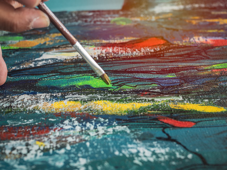 Close-up artist hand painting. Concentrate painting acrylic color on canvas in art studio.の写真素材