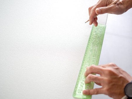 Hands hold the wooden pencil with green ruler on blank white canvas with copy space.