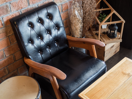Black vintage leather wooden sofa, wooden table, dry flowers and vintage lamp, decoration on brick wall background in loft style cafe.の写真素材