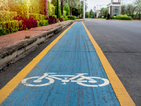 Bike lane. White bicycle icon on blue and yellow background on the old road in the village.の写真素材