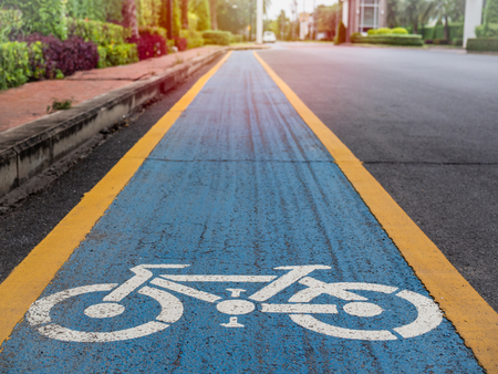 Bike lane. White bicycle icon on blue and yellow background on the old road in the village.の写真素材