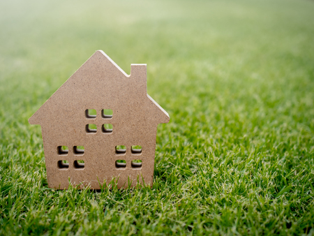 Wooden house on green grass background with copy space. Home ecology conceptの写真素材