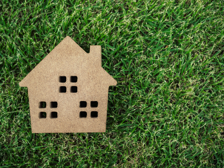 Flat lay wooden house on green grass background with copy space. Home ecology conceptの写真素材