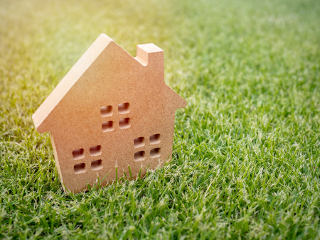 Wooden house on green grass background with copy space. Home ecology conceptの写真素材