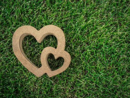 Wooden twin hearts on green grass texture background with copy space. Love concept.の写真素材