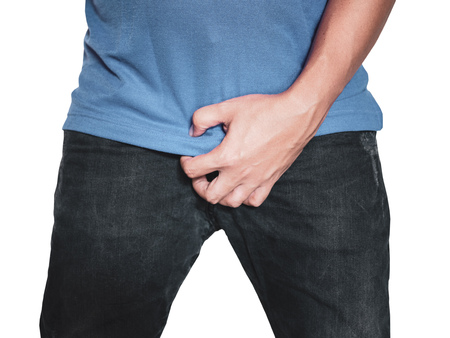 Man hands holding on middle crotch of trousers with pain action isolated on white background.の写真素材