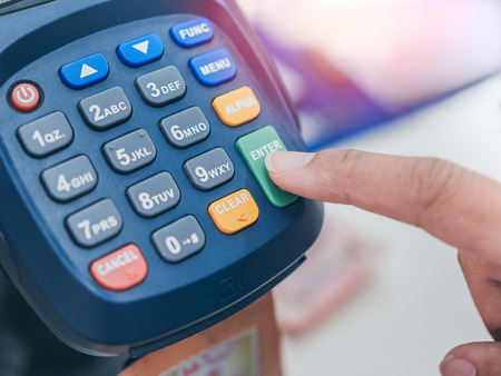 Close up finger push enter button for Credit or debit card password payment on credit card machine.