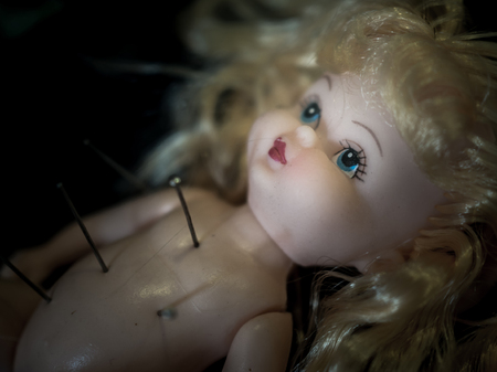 Close-up dirty baby doll blonde hair with pins on dark background. horror and curse conceptの写真素材