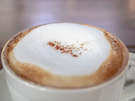 Close up coffee foam of a white cup of hot coffee on wooden table background.の写真素材