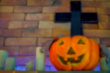 Blurred pumpkin head with white candles and black cross on brick wall background. Happy halloween background concept.の写真素材