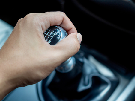 Close-up left hand shifting manually gear on gear stick knob in the car with copy space.の写真素材