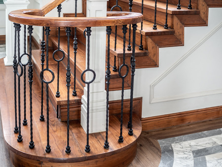Classic vintage elegant wooden staircase with wrought iron railing.