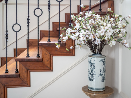 White flower in retro white porcelain home decorative vase. Chinese style Ceramic Vase with classic vintage elegant wooden staircase with wrought iron railing.の写真素材