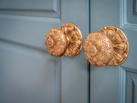 Classic vintage golden door knobs. Antique door knobs with carvings on wooden door.の写真素材