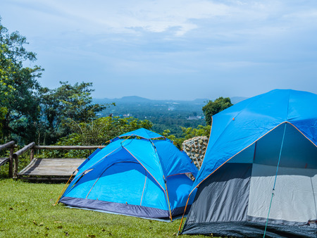 Camping blue tents on green grass with the mountain and blue sky view.の写真素材