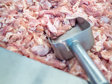 Pile of fresh chicken in a container with a scoop in the supermarket.の写真素材