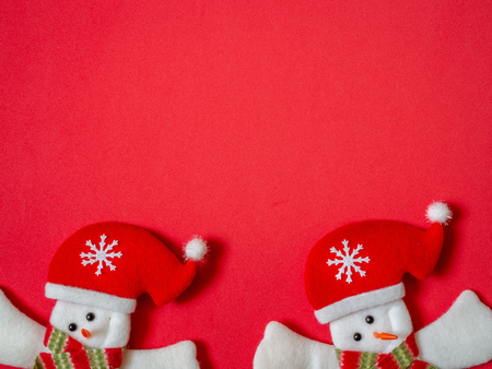 Cute happy snowman wearing Santa Claus hat on red background with copy space. Christmas minimalist background concept.の写真素材