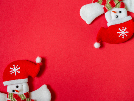 Cute happy snowman wearing Santa Claus hat on red background with copy space. Christmas minimalist background concept.の写真素材