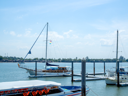 Luxury yachts docked in seaport. Marina parking of modern motor boats on the sea with the fisherman village and blue sky background on sunny day at krabi, Thailand.の写真素材