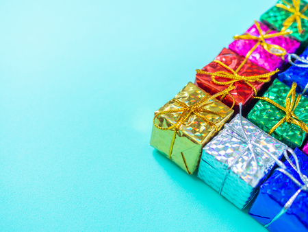 Small colorful gift boxes on light marine blue background with copy space. Top view of many gifts wrapped colorful shiny paper.の写真素材