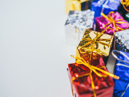 Close-up small colorful gift boxes on white background with copy space. Many gifts wrapped colorful shiny paper.の写真素材