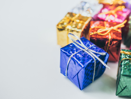 Close-up small colorful gift boxes on white background with copy space. Top view of many gifts wrapped colorful shiny paper.の写真素材
