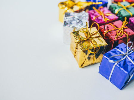 Small colorful gift boxes on white background with copy space. Top view of many gifts wrapped colorful shiny paper.の写真素材