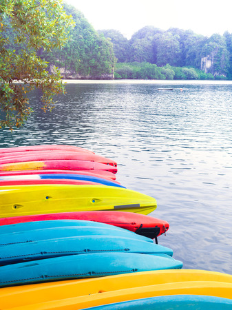 Row of colorful fiberglass kayaks on seascape and mountain background with copy space vertical style.の写真素材